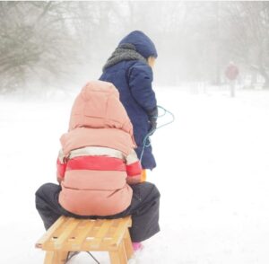 2 children in snow with sled